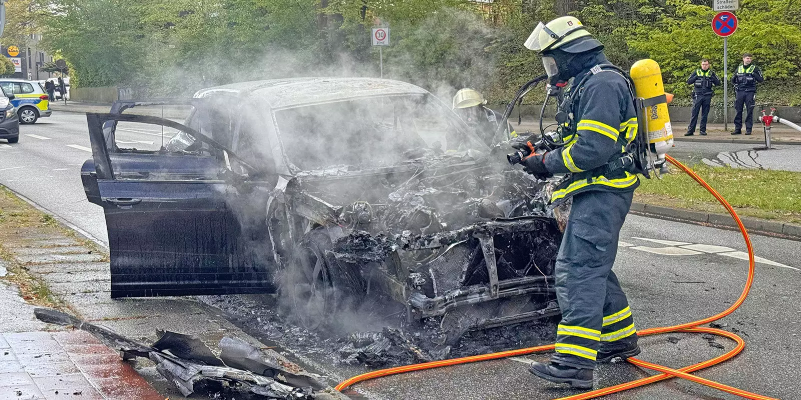 Feuerwehrleute an dem ausgebrannten Porsche. Foto: Lenthe-Medien