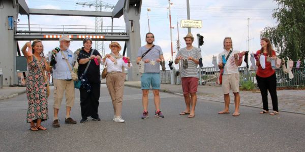 Künstler und Helfer im Einsatz auf der Klappbrücke: Sie transormieren die einzelnen Socken in eine Sockenkette. Foto: cb Harburger Socken