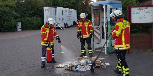 Feuerwehrleute löschen. Foto: Matthias Köhlbrandt Brennende Büchereitelefonzelle: Anwohner löschen mit Gießkannen