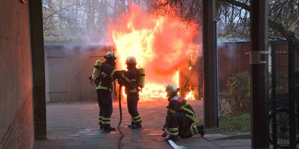 Feuerwehrleute beginnen mit den Löscharbeiten. Foto: MüGü Buxtehuder Straße: Garage auf Hinterhof brannte lichterloh