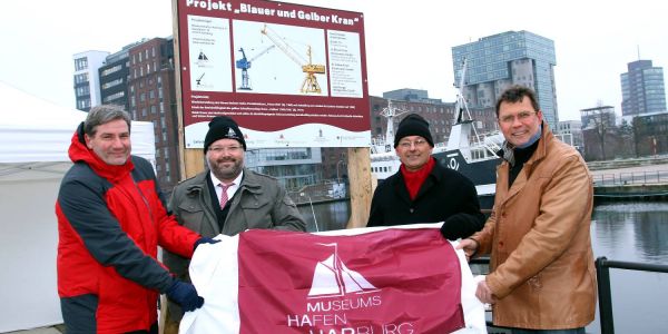 Metin Hakverdi (von links), Helgo Mayrberger, Gorch von Blomberg und Jens Alsleben von Konecranes enthüllen das Bauschild am Lotsekai. Foto: Christian Bittcher Startschuss im Binnenhafen: Blauer Kran wird für 300.000 Euro saniert