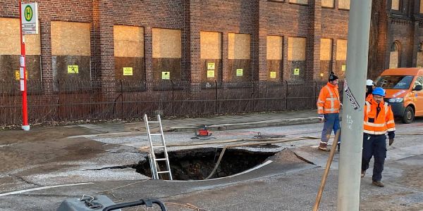 Das Loch in der Neuländer Straße. Über eine Leiter steigen Experten in den Hohlraum unter der Straße. Foto: André Zand-Vakili Nach Wasserrohrbruch: Teil der Neuländer Straße gesperrt
