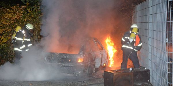 Feuerwehrleute löschen den brennenden Opel. Foto: Andre Lenthe Fotografie Opel Astra ohne Kennzeichen brennt nahe der Flutschutzwand