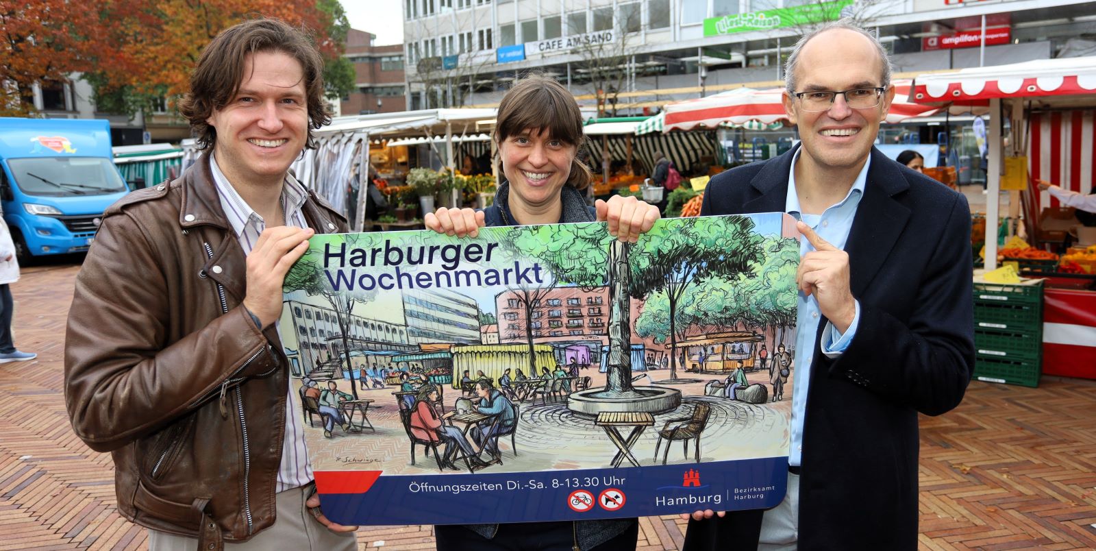 Bezirksamtsleiter Christian Carstensen (von rechts), Marktmeisterin Johanna Eisenschmidt und Maler Ralf Schwinge mit dem neuen Marktschild. Foto: Christian Bittcher