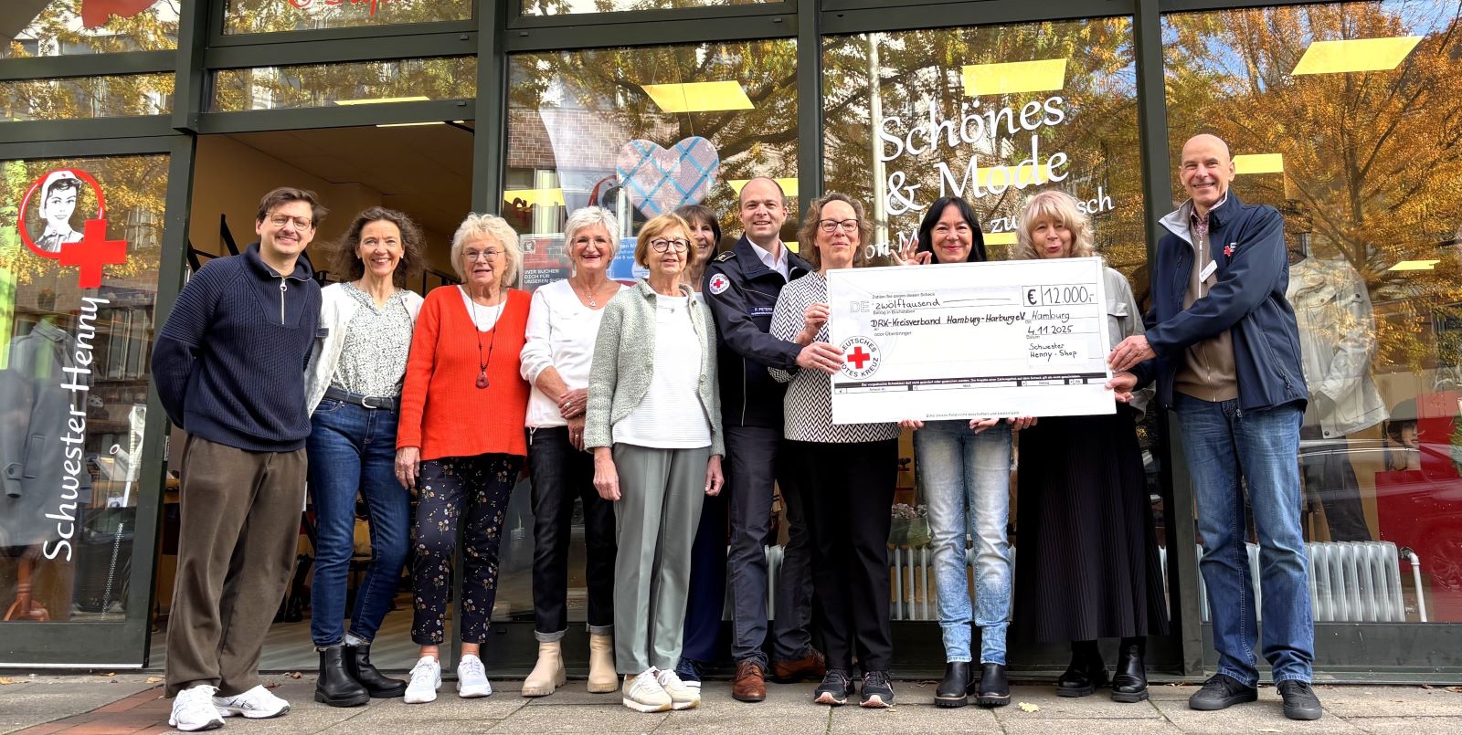 Das Team von &quot;Schwester Henny&quot; mit den Vertretern der bedachten DRK-Projekte vor dem Shop am Harburger Ring 8-10. Foto: DRK-Harburg