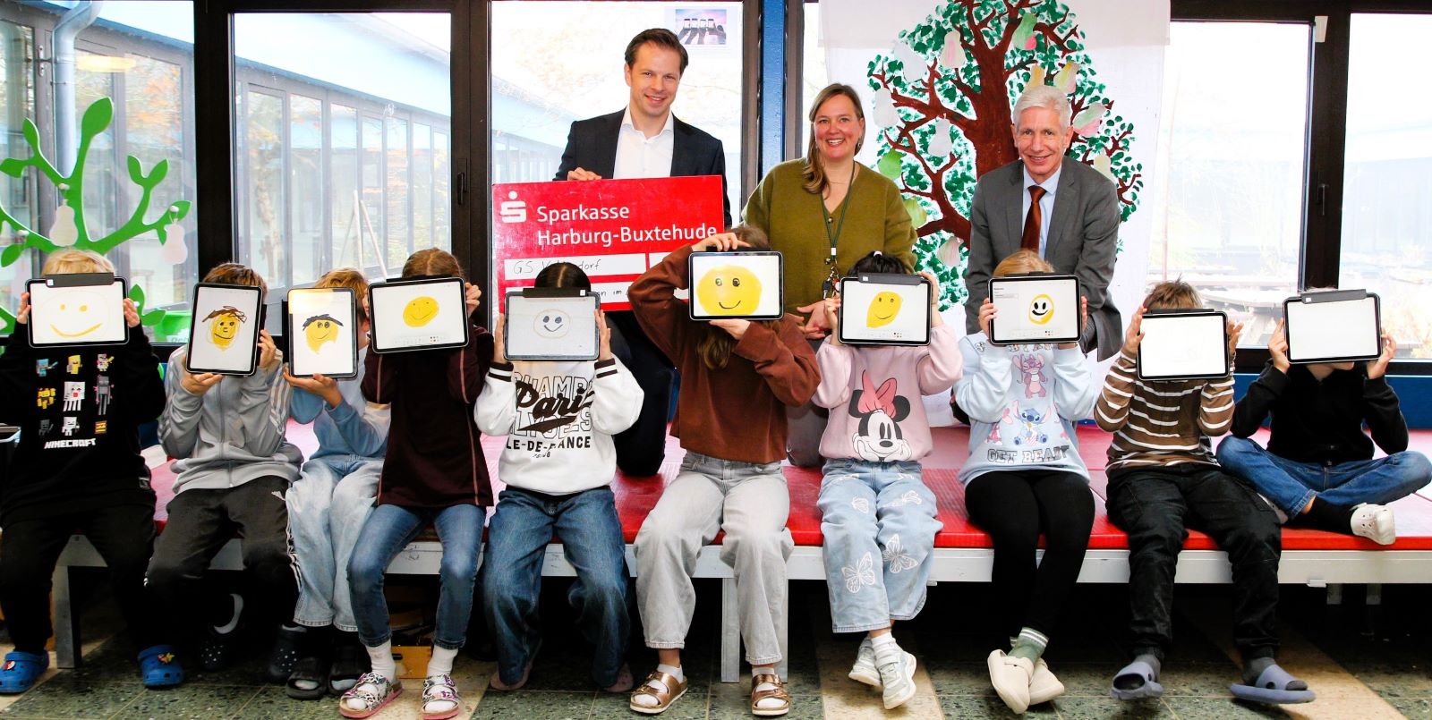 Landrat Rainer Rempe (rechts) und Frederik Schröder, Vorstandsmitglied der Sparkasse Harburg-Buxtehude, übergeben das Preisgeld an Schulleiterin Katharina General. Foto: Landkreis