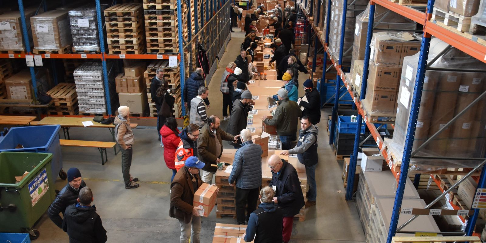 An einer langen Packstraße verstauten die Helfenden, die zwischen sieben und 85 Jahren alt waren, die einzelnen Utensilien wie Mehl, Zucker, Reis und Nudeln, Seife, Schokolade und ein kleines Geschenk für Kinder in die Kartonagen. Foto: Johanniter
