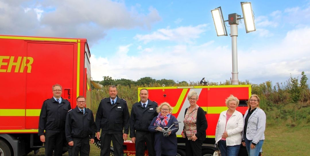 Über die Indienststellung des neuen Lichtmastanhängers und der neuen Drohne freuen sich v.l. Clemens Cohrs (FF Ramelsloh), Simon Steffen (FF Hittfeld), Andreas Brauel, Rainer Wendt, Angelika Tumuschat-Bruhn (mit Drohne), Bürgermeisterin Emily Weede und die Ausschussmitglieder Berit Rohte und Nicole Bathke. Foto: Feuerwehr