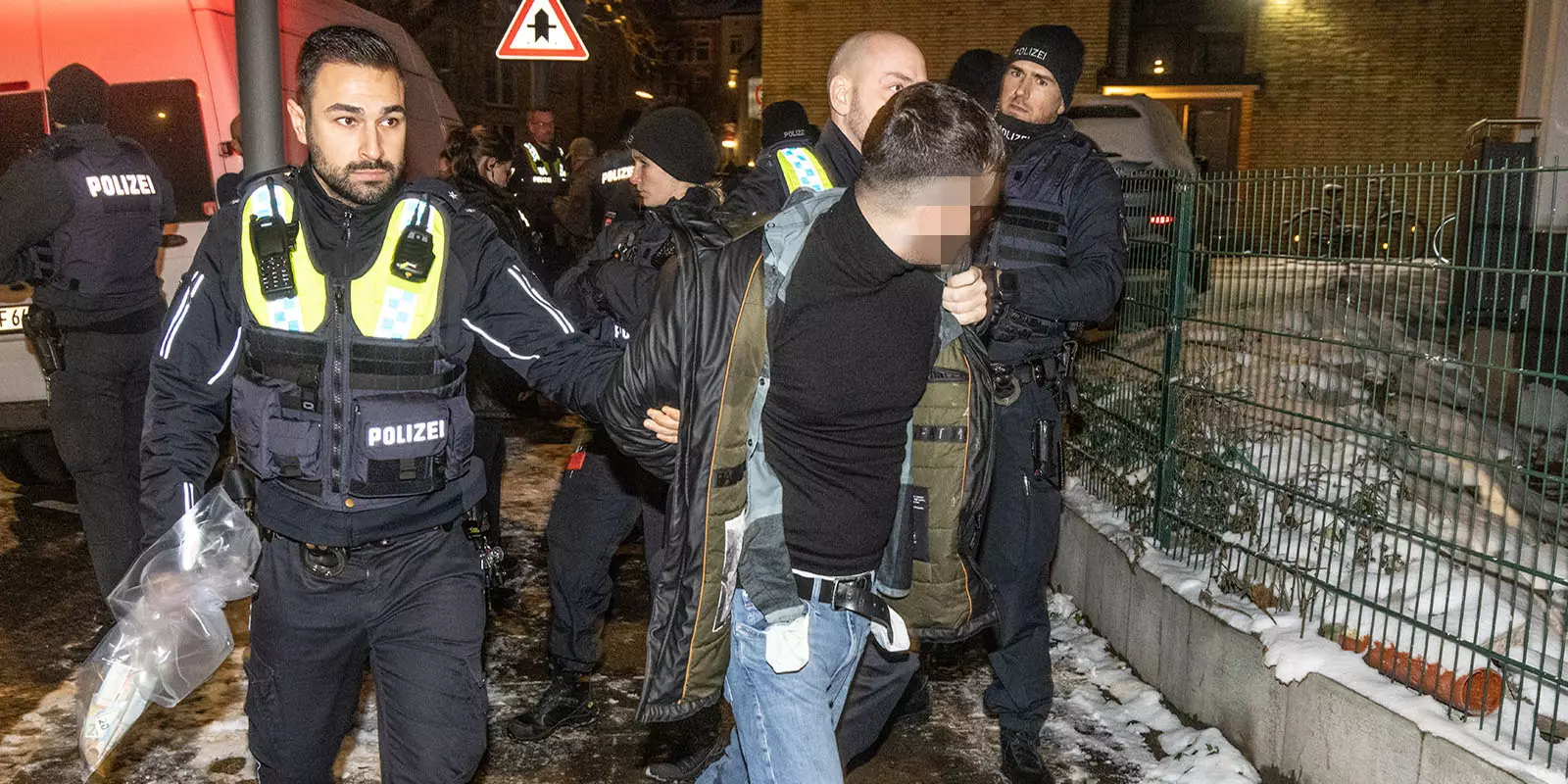 Polizisten führen einen der Festgenommenen ab. Foto: zv