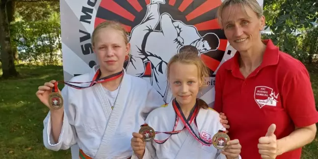 Mara Wilkens und Jenna Geerdts freuen sich mit Trainerin Bianca Geerdts über die Medaillen. Foto: pr