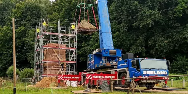 Das Dach vom Trafoturm wird mit Hilfe eines Krans aufgesetzt. Foto: FLMK