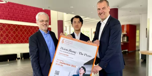 Andreas Sommer, Vorstandsvorsitzender der Sparkasse Harburg-Buxtehude (von rechts), Haiou Zhang und Empore-Geschäftsführer Onne Hennecke mit dem Plakat für das Konzert des Ausnahmepianisten in der Empore Buchholz.