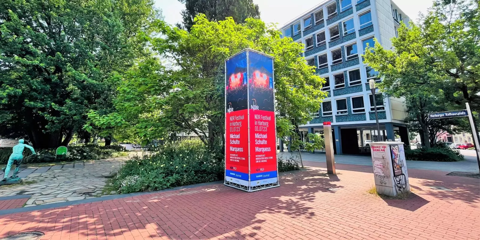 Eine große eckige Werbetafel am Rathausplatz weist auf die Veranstaltung hin. Foto: Christian Bittcher