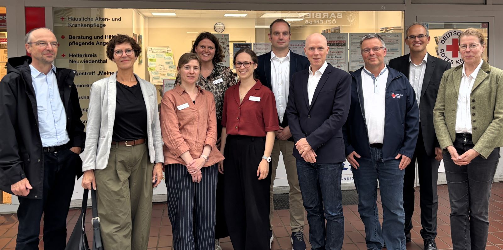 Vor dem DRK-Stadtteiltreff: Staatsrat Angerer (4 v.r.) mit Referatsleiter und -leiterin (links) sowie DRK-Harburg Vorstand Harald Halpick (3.v.r.), Bezirksamtsleiter Christian Carstensen (2. v.r.) und Sozialdezernatsleiterin Dr. Anke Jobman (r.) mit dem Team des "Wohnen bleiben im Quartier"-Projekts in Neuwiedenthal. Foto: DRK